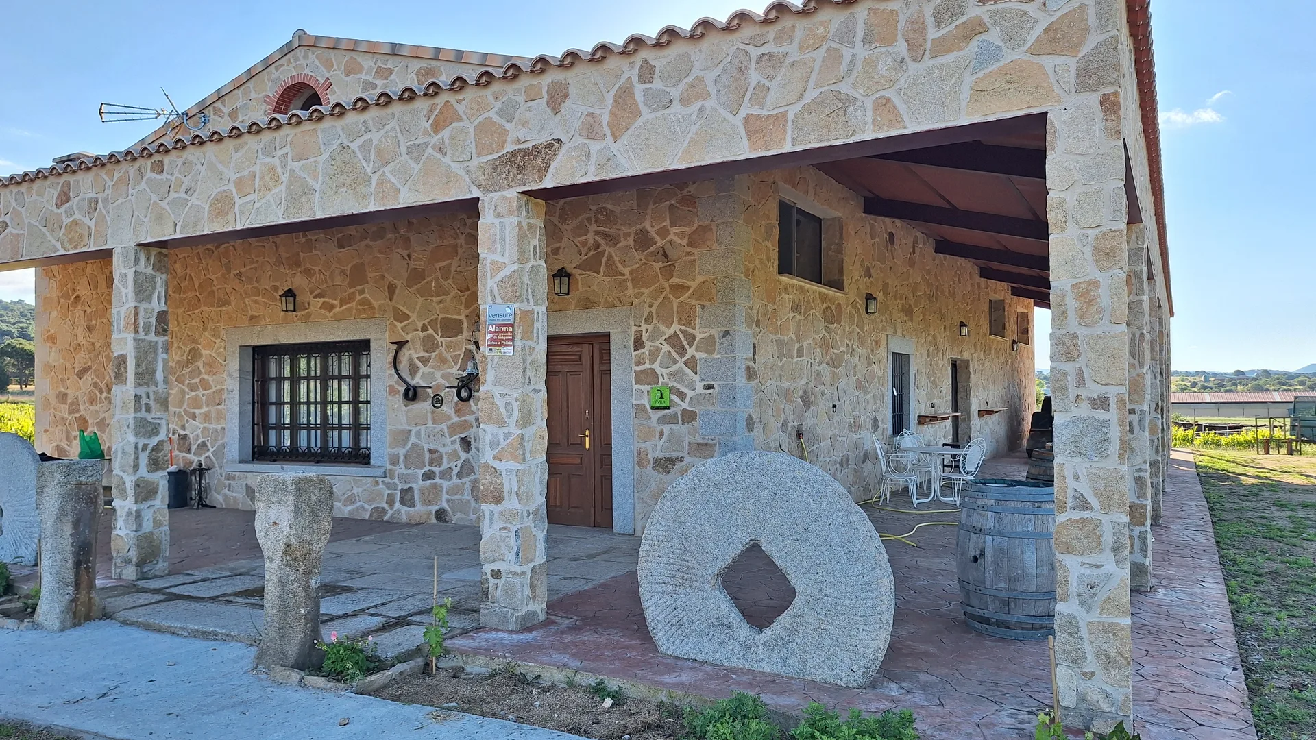 Entrada de la casa con piedra de molino y barrica